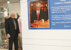 Salvatore standing near a plaque at the John R. Oishei Children’s Hospital. All TV sets at the children’s hospital were donated by him.