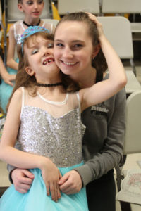 The bond between dancers and volunteers is strong, as shown here as Aria Lewis and Jillian Szeluga embrace before they hit the stage.