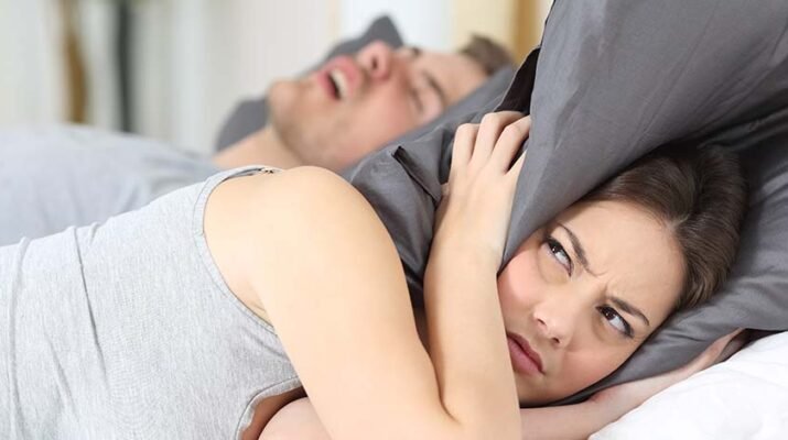 Woman covering her ears with pillow